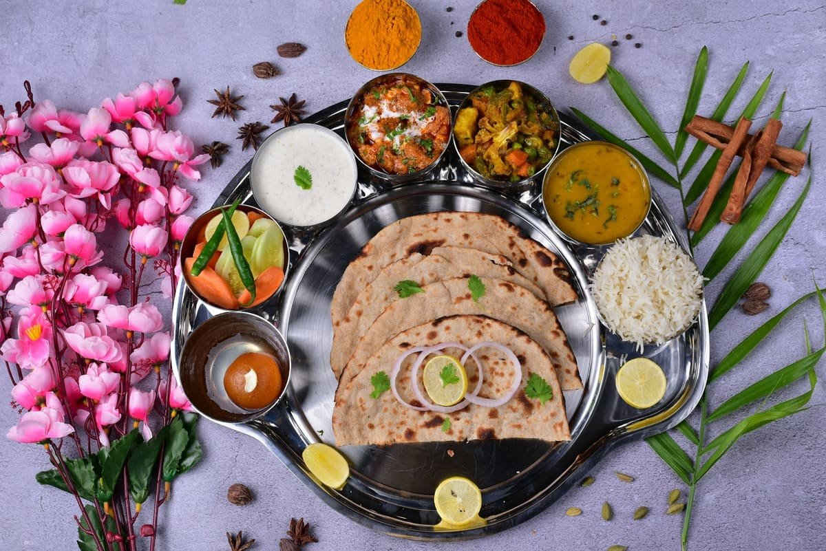 A vegetarian thali with paneer, mixed vegetables, dal, rice, raita, salad, roti and gulab jamun