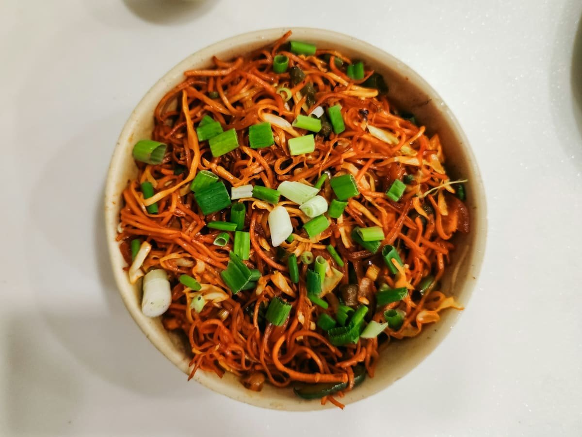 A bowl of vegetable hakka noodles with spring onion