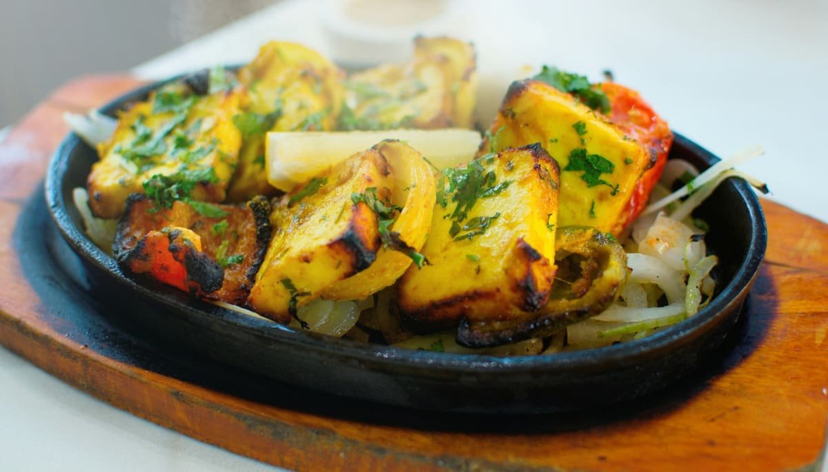 Paneer tikka with grilled peppers and onion on a hot sizzler plate