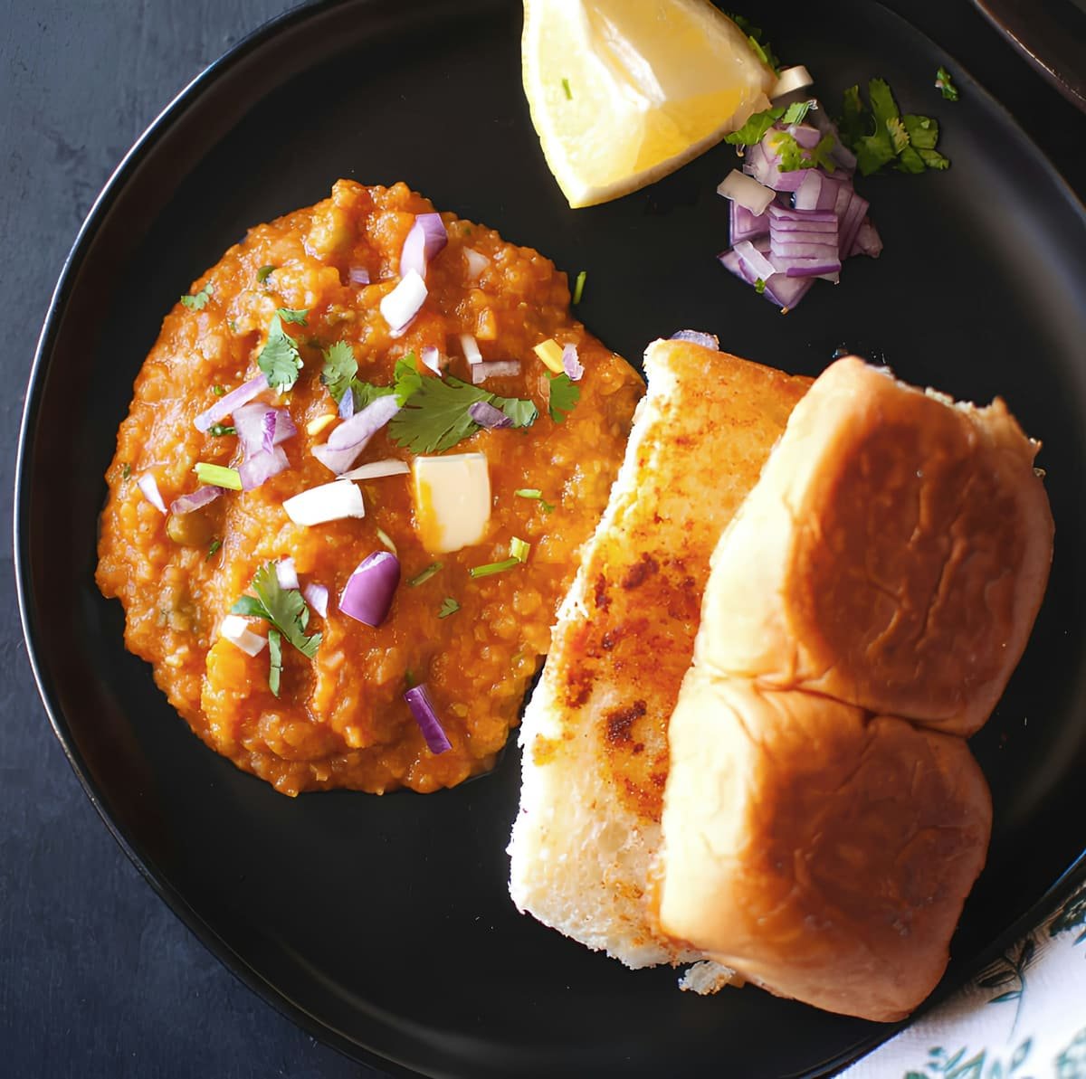Pav bhaji topped with butter, onion and coriander with toasted pav