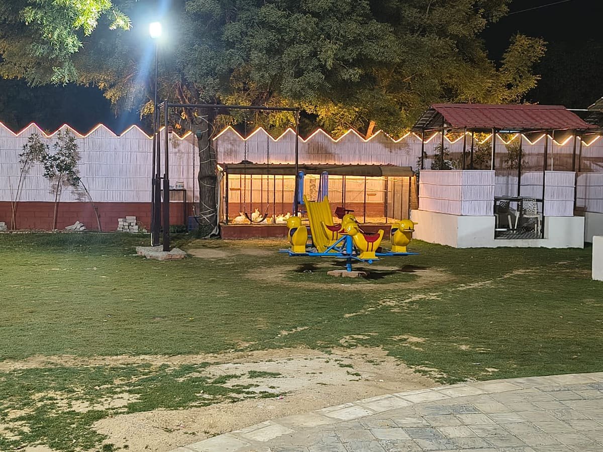 The kids play area with swings and rides beside the lawn at The Garden, Jagatpura